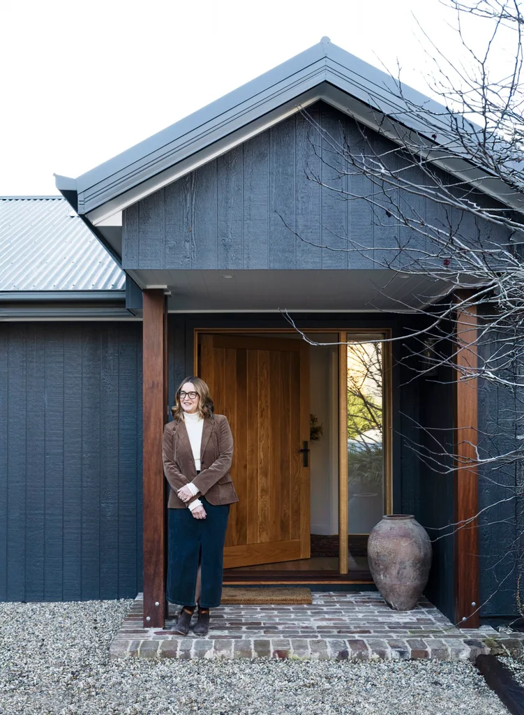 Interior designer Kate Hardy stood outside her black timber panelled home in the Southern Highlands