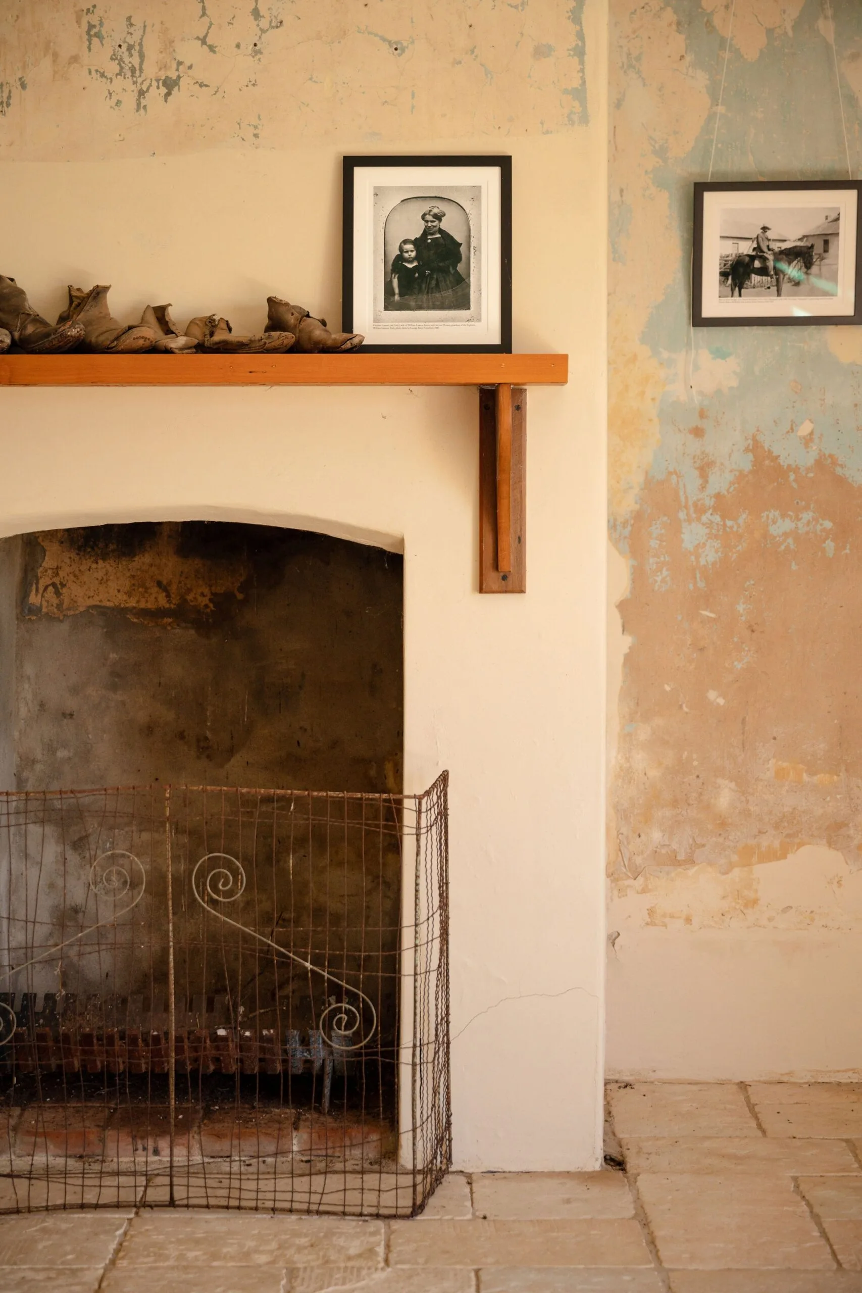 An old Georgian fireplace with black and white photos hanging above