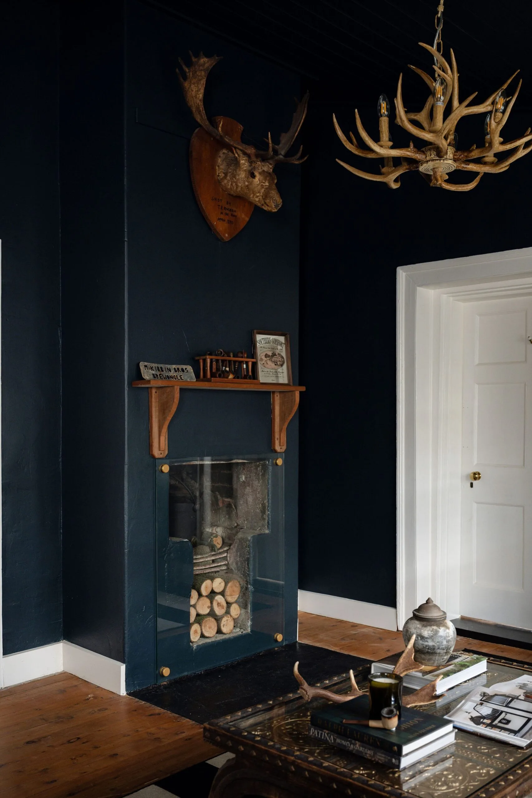 A dark blue sitting room with a deer head ornament and small fireplace