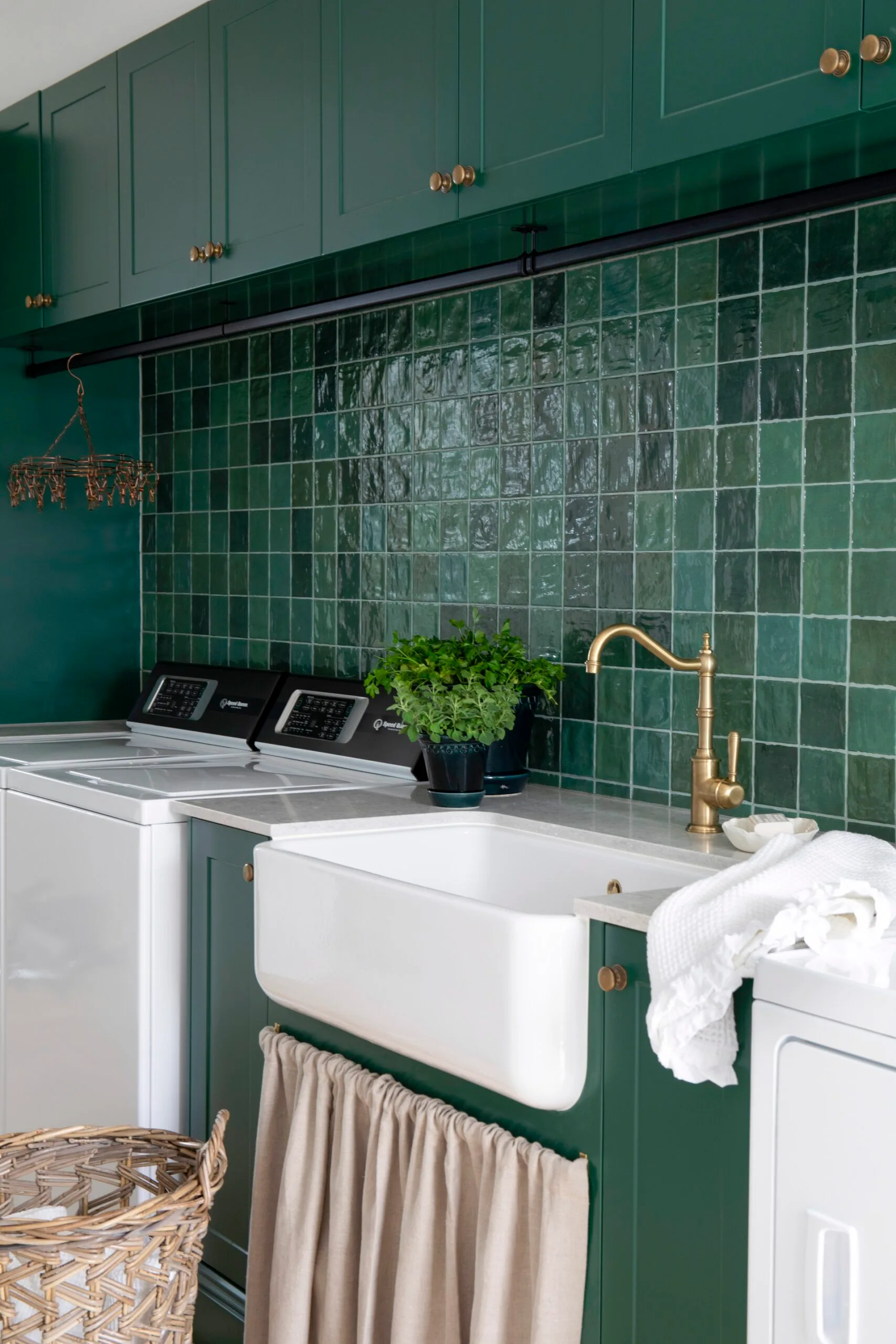 Green laundry with zellige tiles, a farmhouse sink, and brass tapware