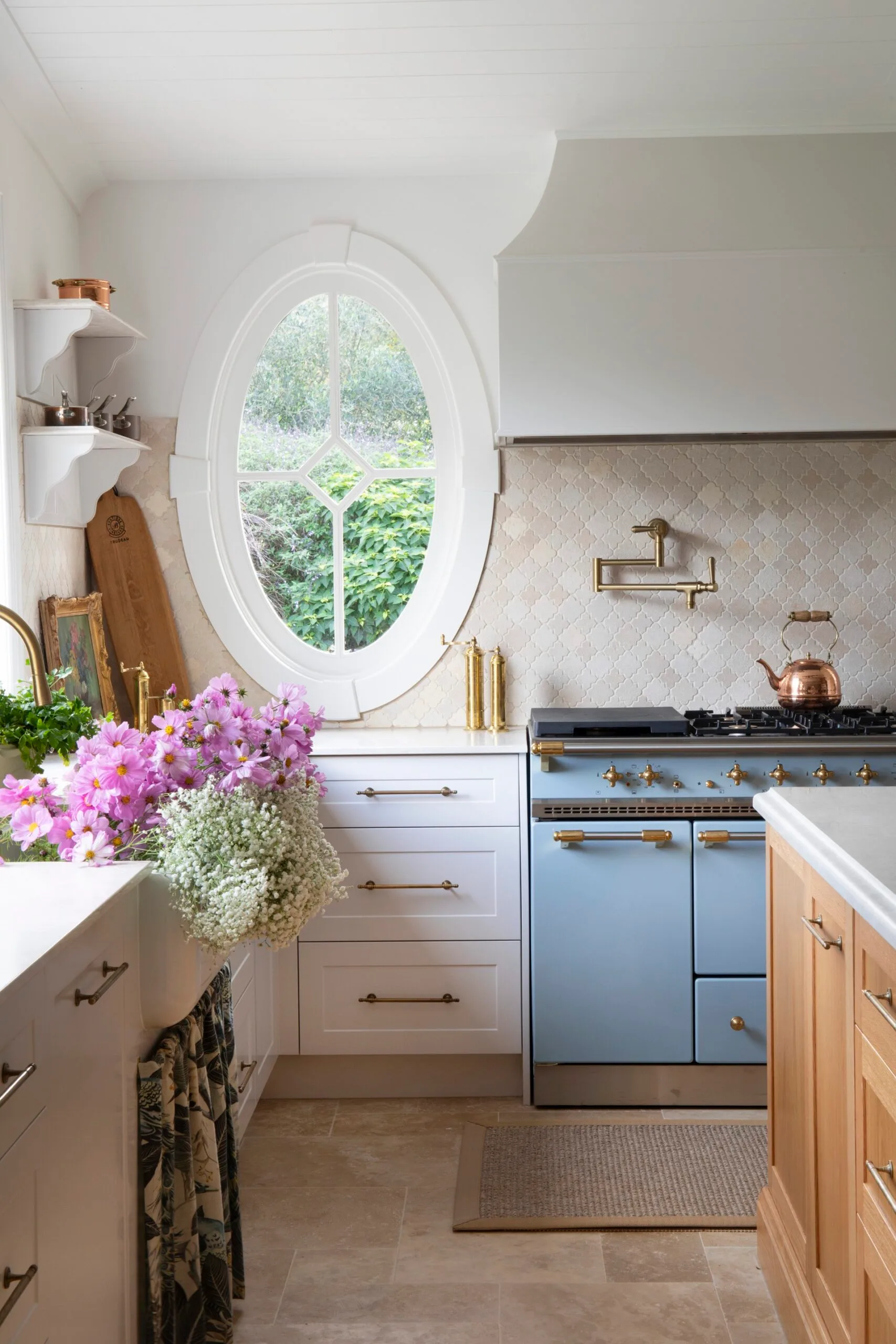 Farmhouse kitchen with a blue oven, an oval window, and a Zellige tiled splashback