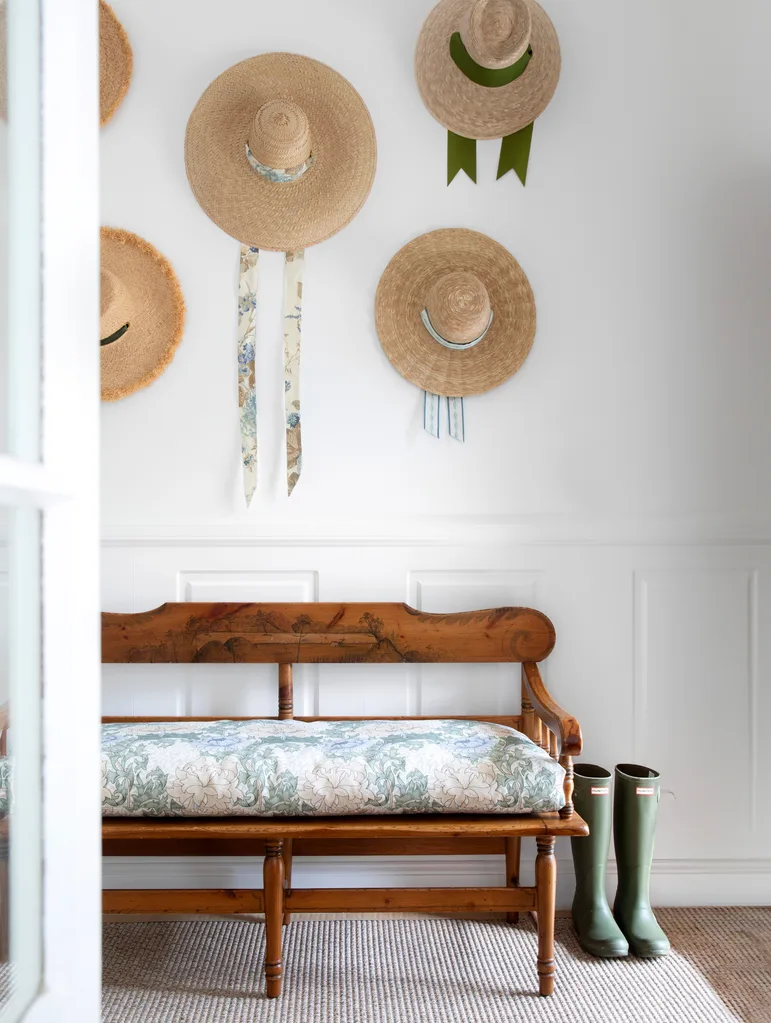 Hallway or entry with white wainscoting, a vintage bench seat, and a display of hats on the wall