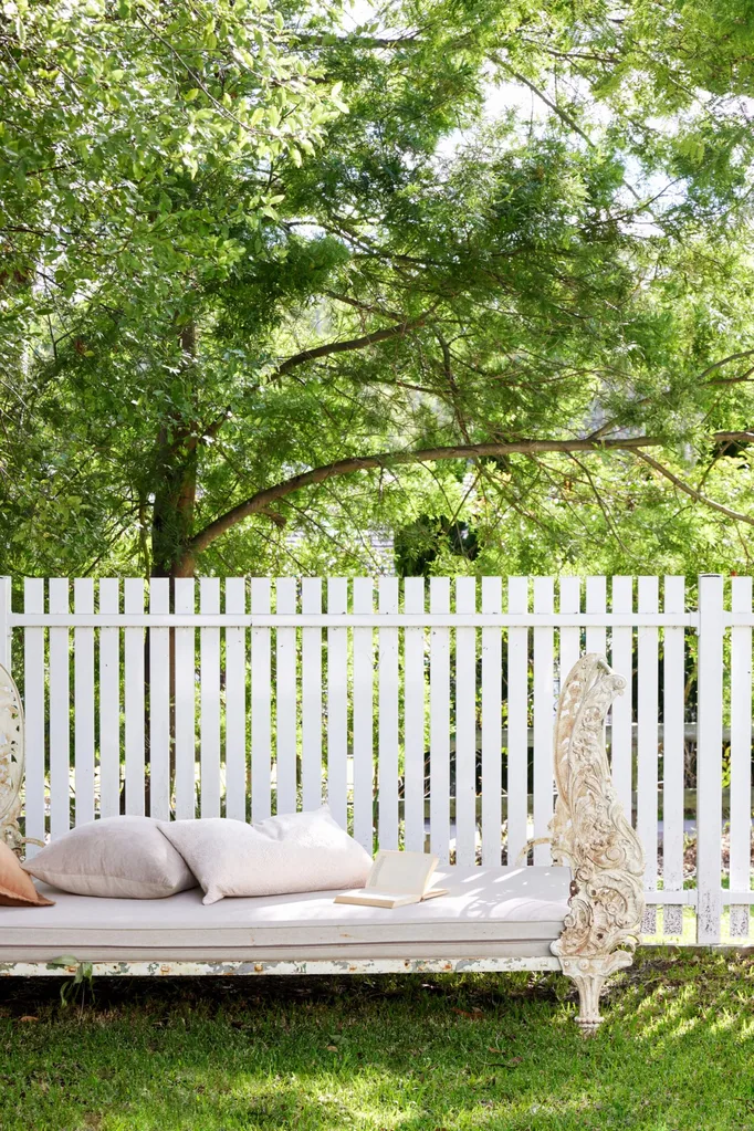 Outdoor bench seat and white picket fence in a garden.