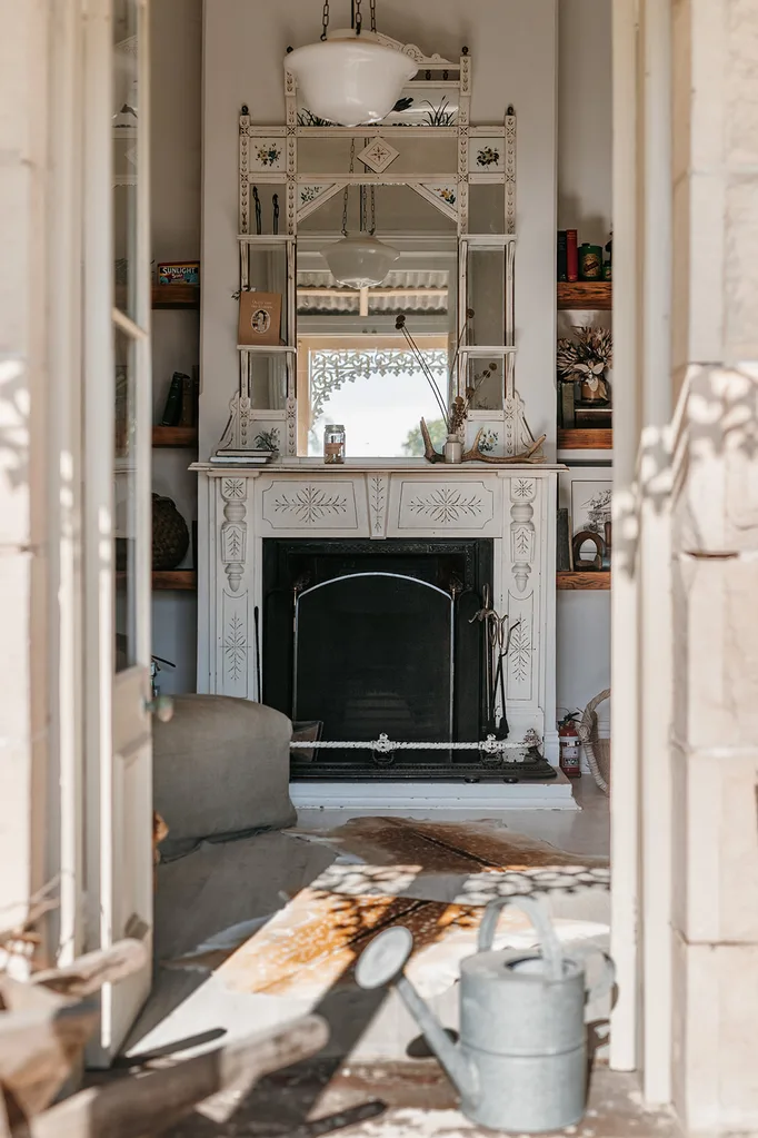 Looking through french doors to a sitting room with an antique fireplace