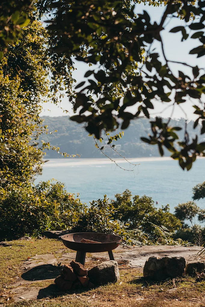 A view over a fire pit towards a coastal scene