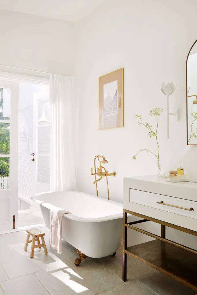 White bathroom featuring a clawfoot bathtub and brass hardware.
