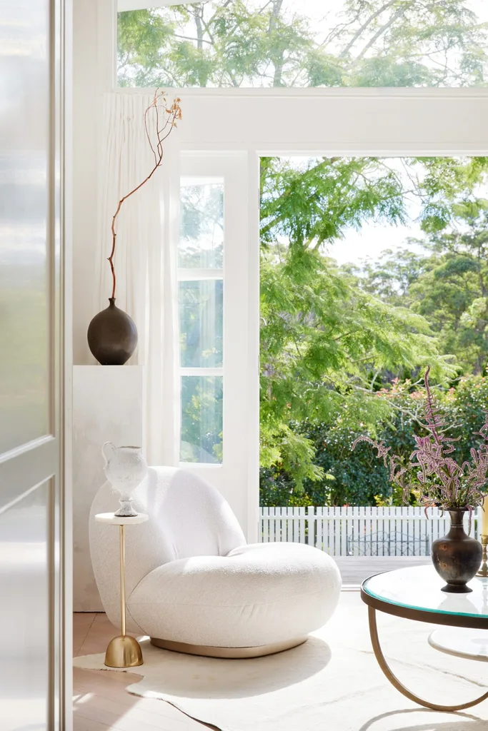 White interior featuring a chunky Gubi armchair, a brass coffee table, and a gold side table.