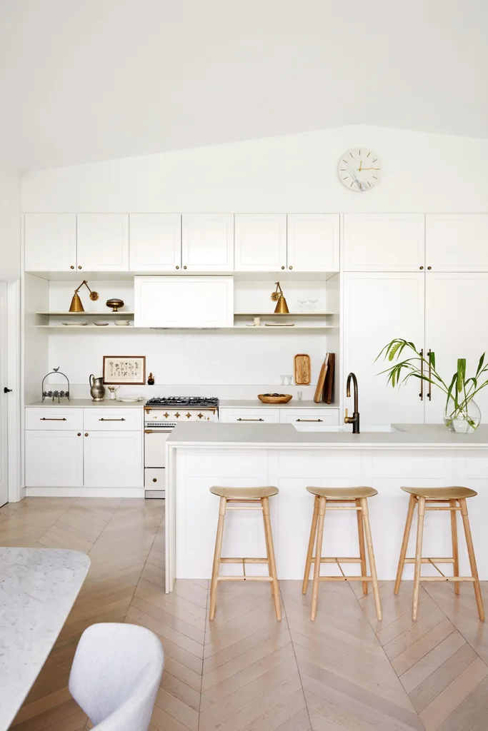 The kitchen has white shaker cabinets, oak floors and brass accents.