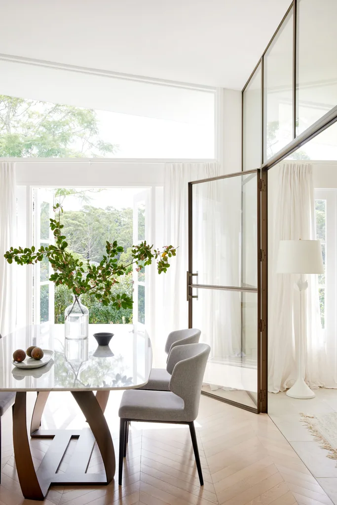 A white, neutral dining room including steel doors and Domo chairs.