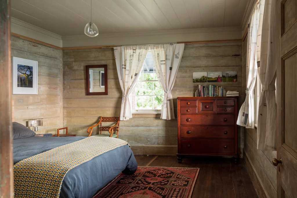 A bedroom within Captain Kelly's Cottage with rustic timber panelling and sash windows