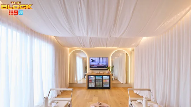 Two arched mirrors on either side of a mounted television atop a fridge in the Pilates studio of Britt and Taz on The Block.