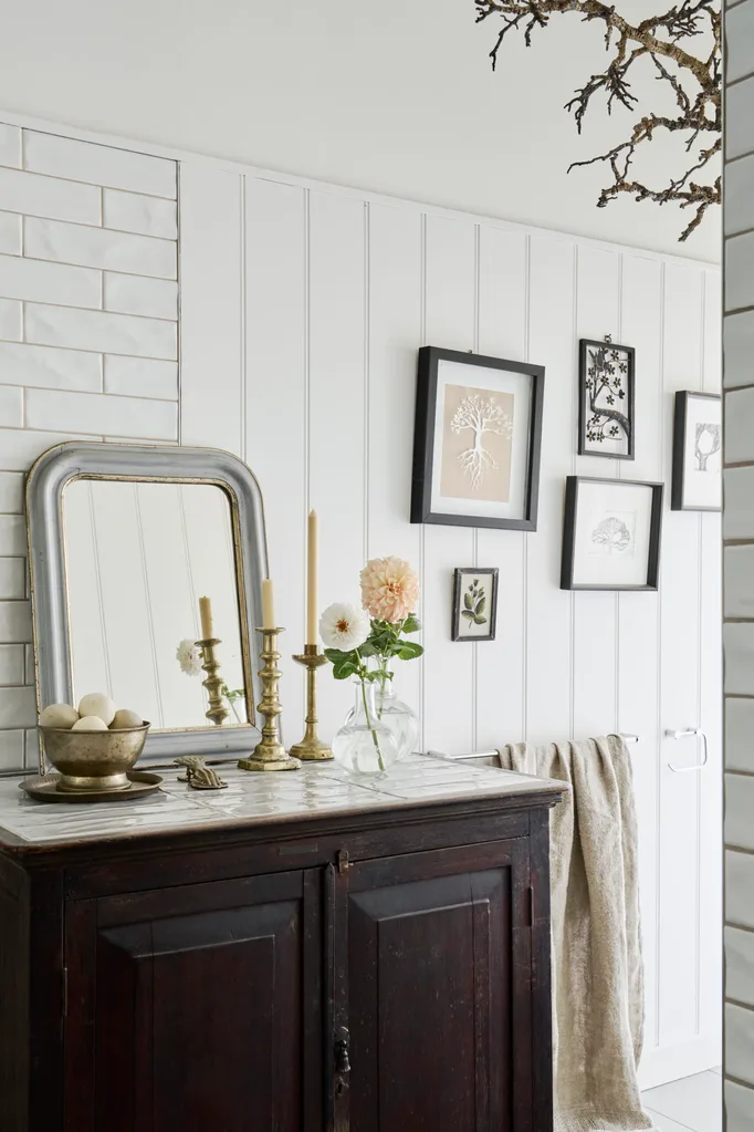 A bathroom with a small vintage vanity and gallery wall