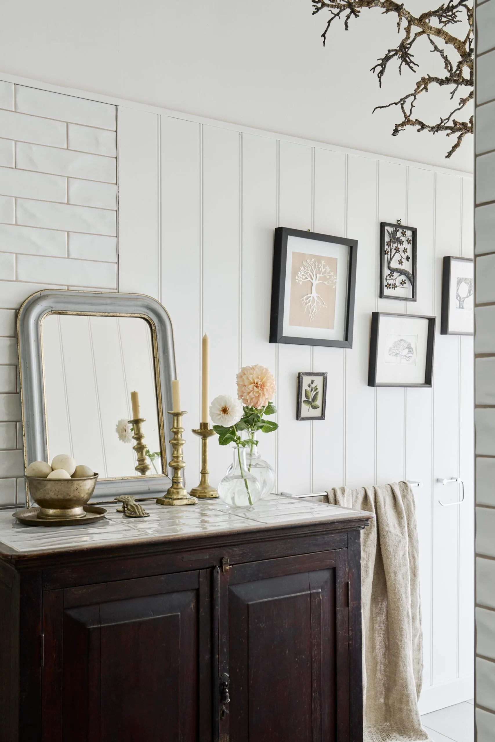 A bathroom with a small vintage vanity and gallery wall