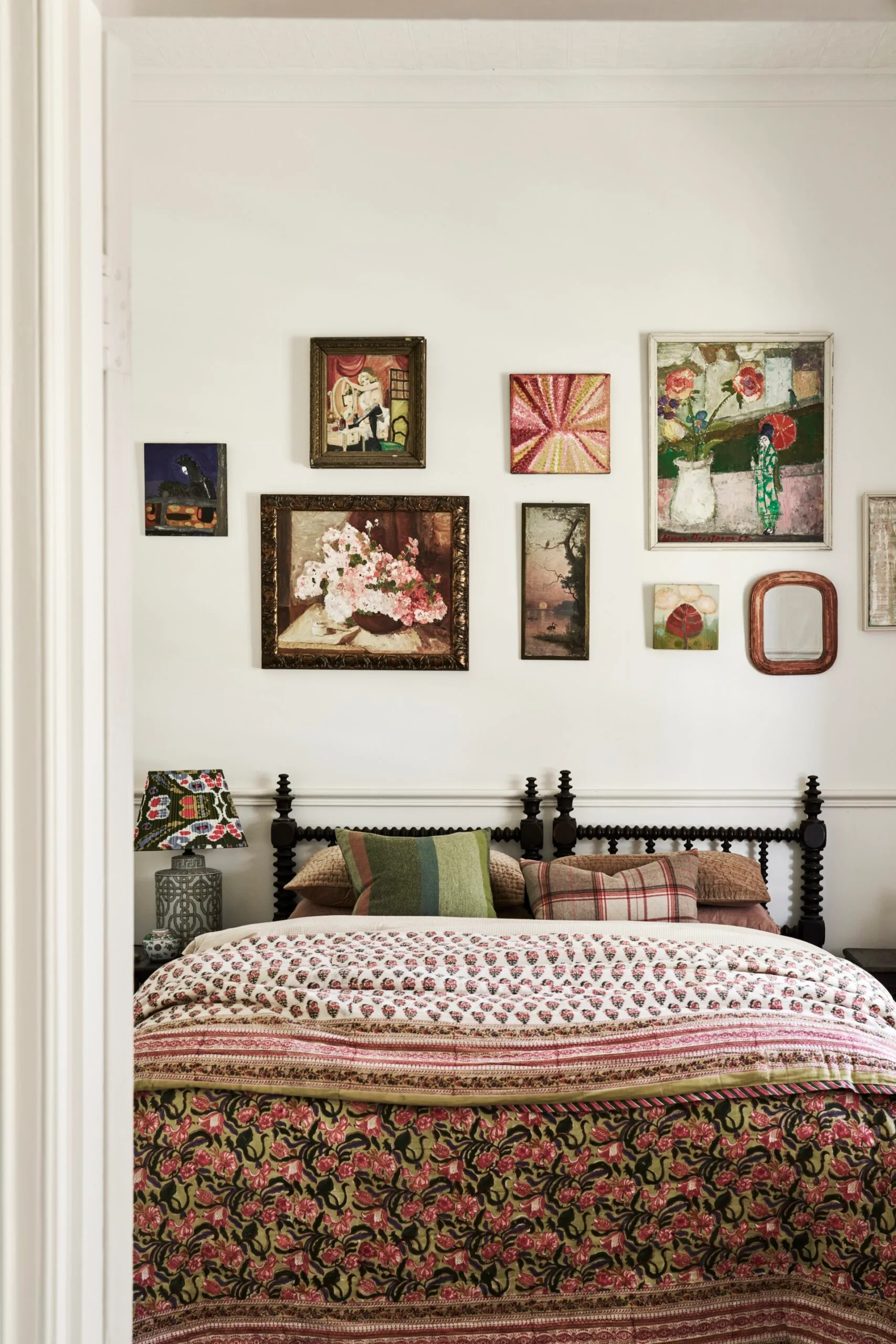 A bedroom with a gallery wall and floral bedding