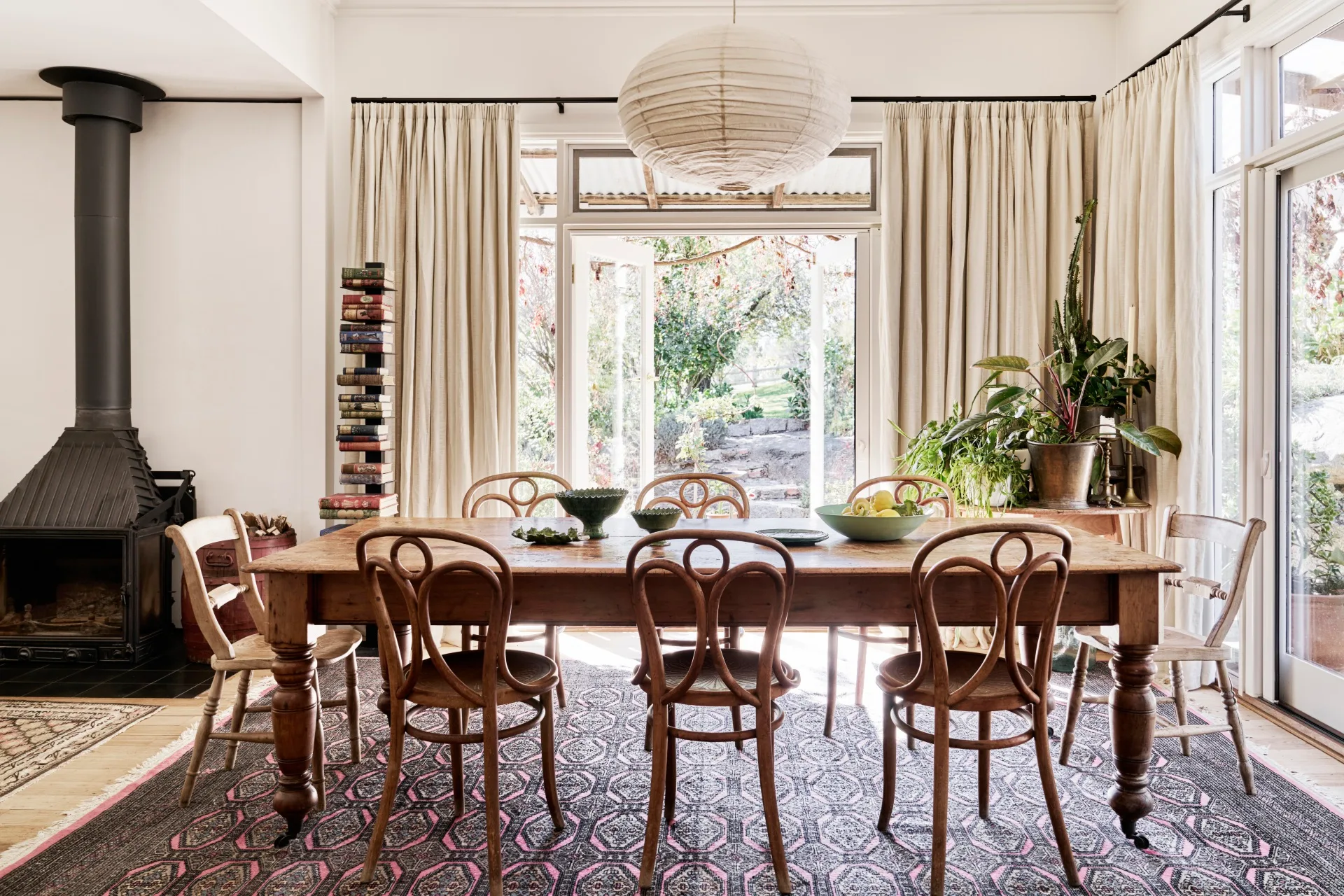 A dining room with a large pink and black rug and a timber dining setting