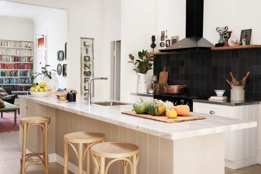 A white kitchen with a black tiled splashback and timber stools