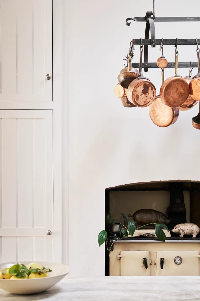 A white kitchen with copper pans hanging from the ceiling