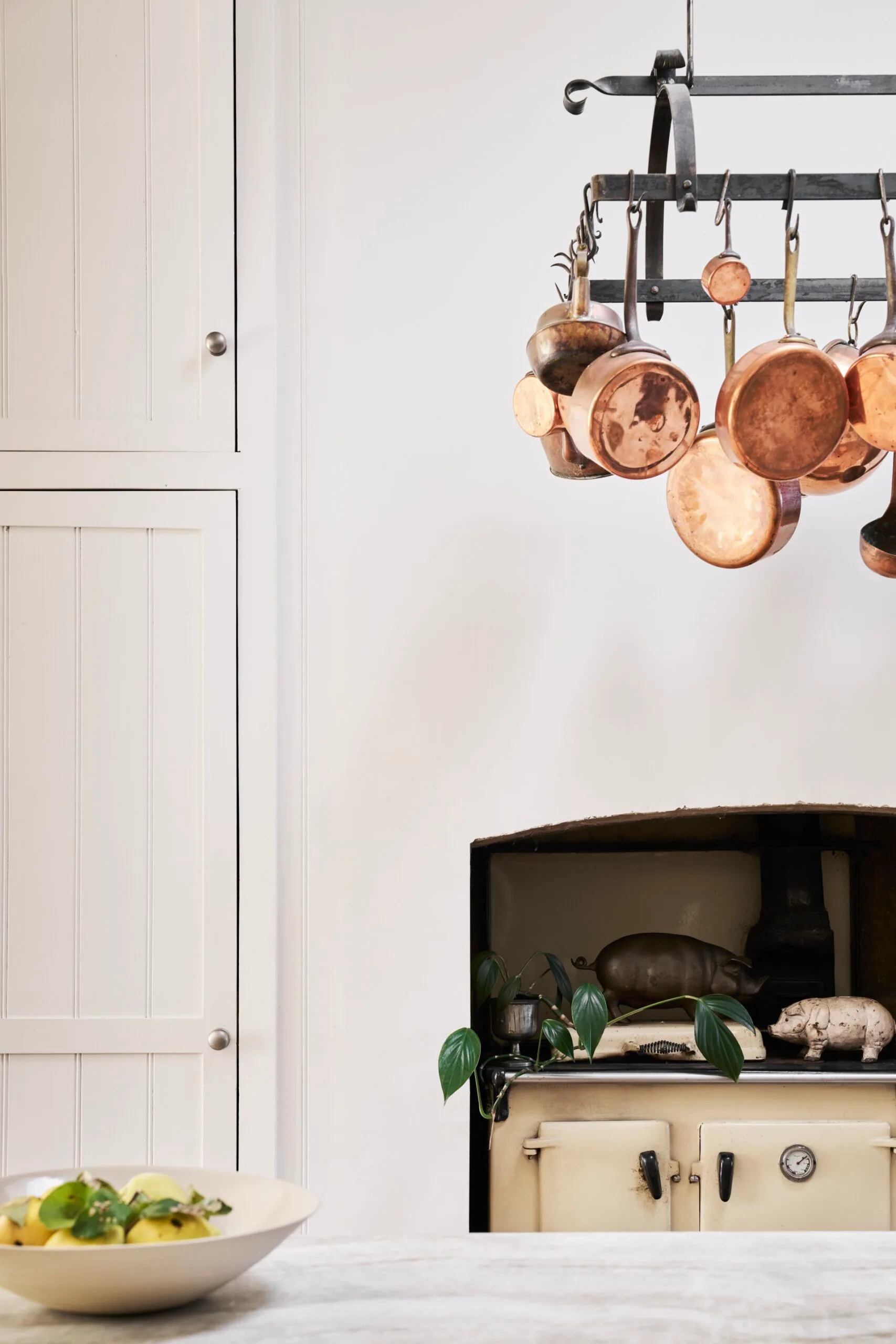 A white kitchen with copper pans hanging from the ceiling