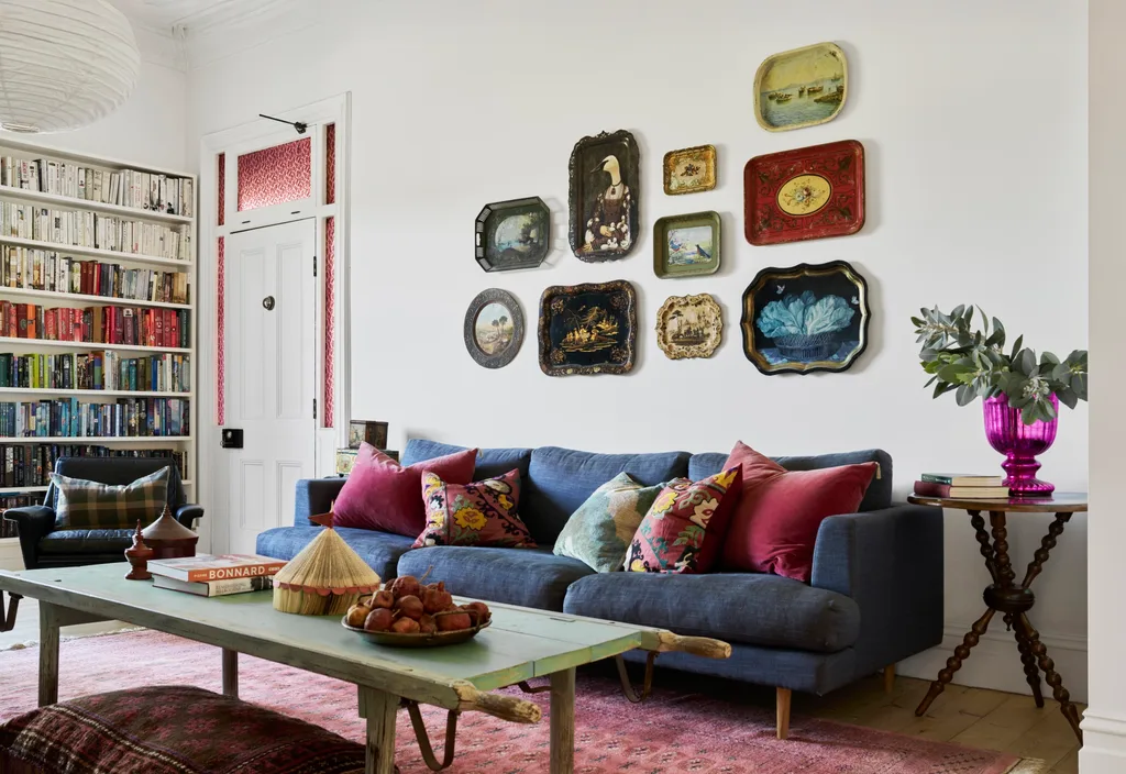 A lounge area with a gallery wall of decorative trays and colour coded bookshelves