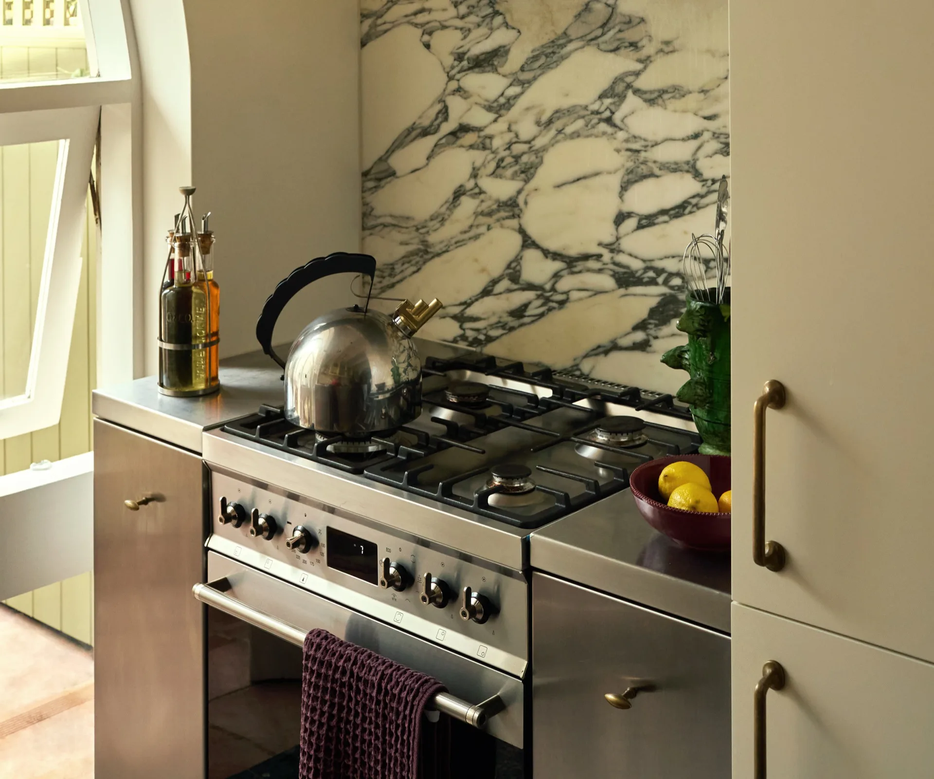 A stovetop with calacatta marble backsplash.