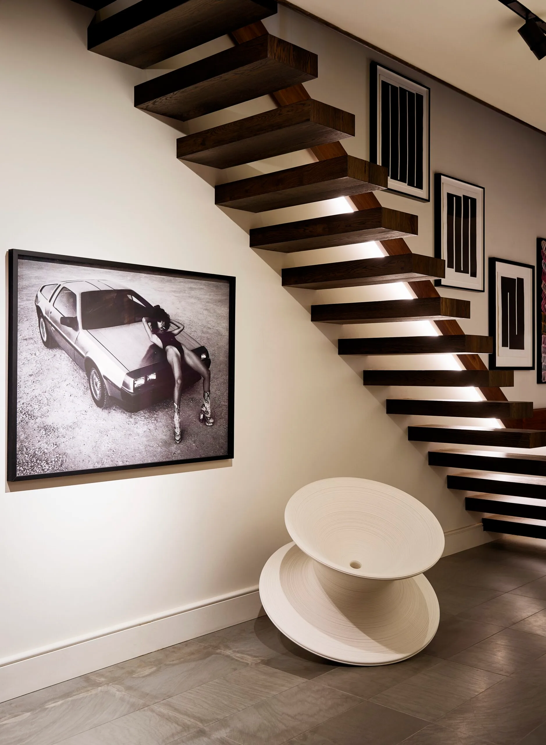 A floating timber staircase and framed black and white artworks on the wall