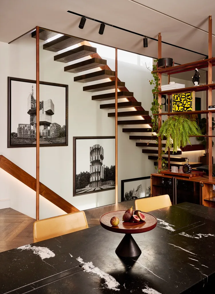 A dining area beside a floating staircase and open timber shelving