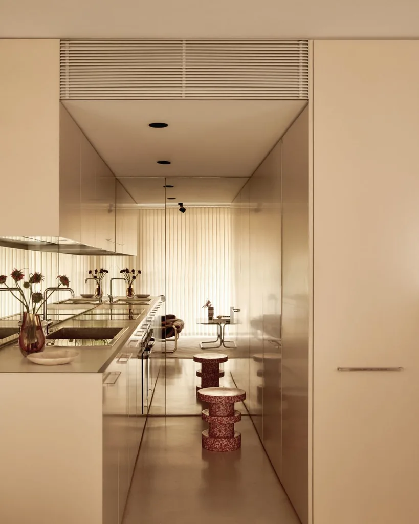 A galley-style kitchen with mirrored splashback and cream cabinets.