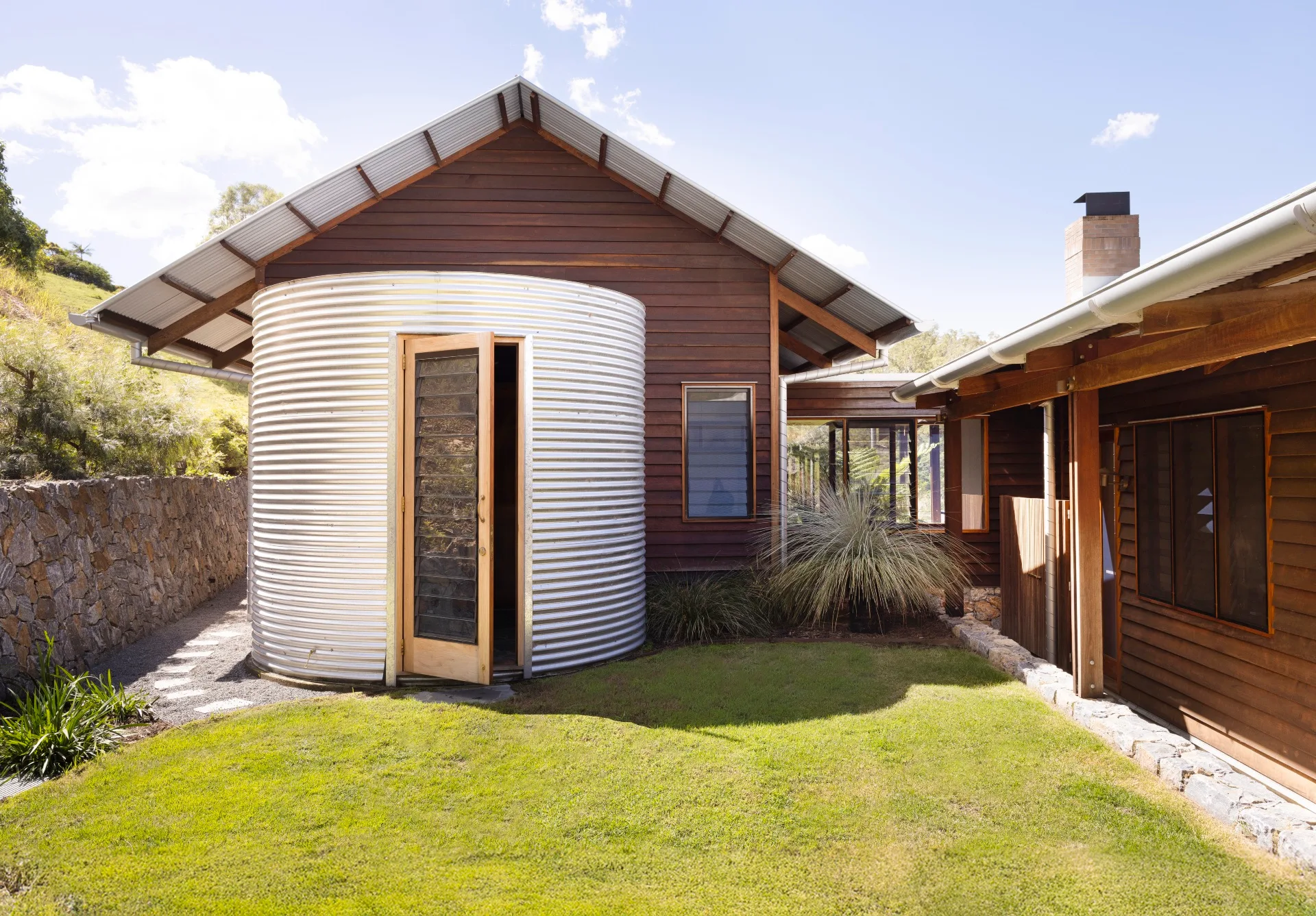 A timber clad home with a repurposed metal drum acting as a mudroom