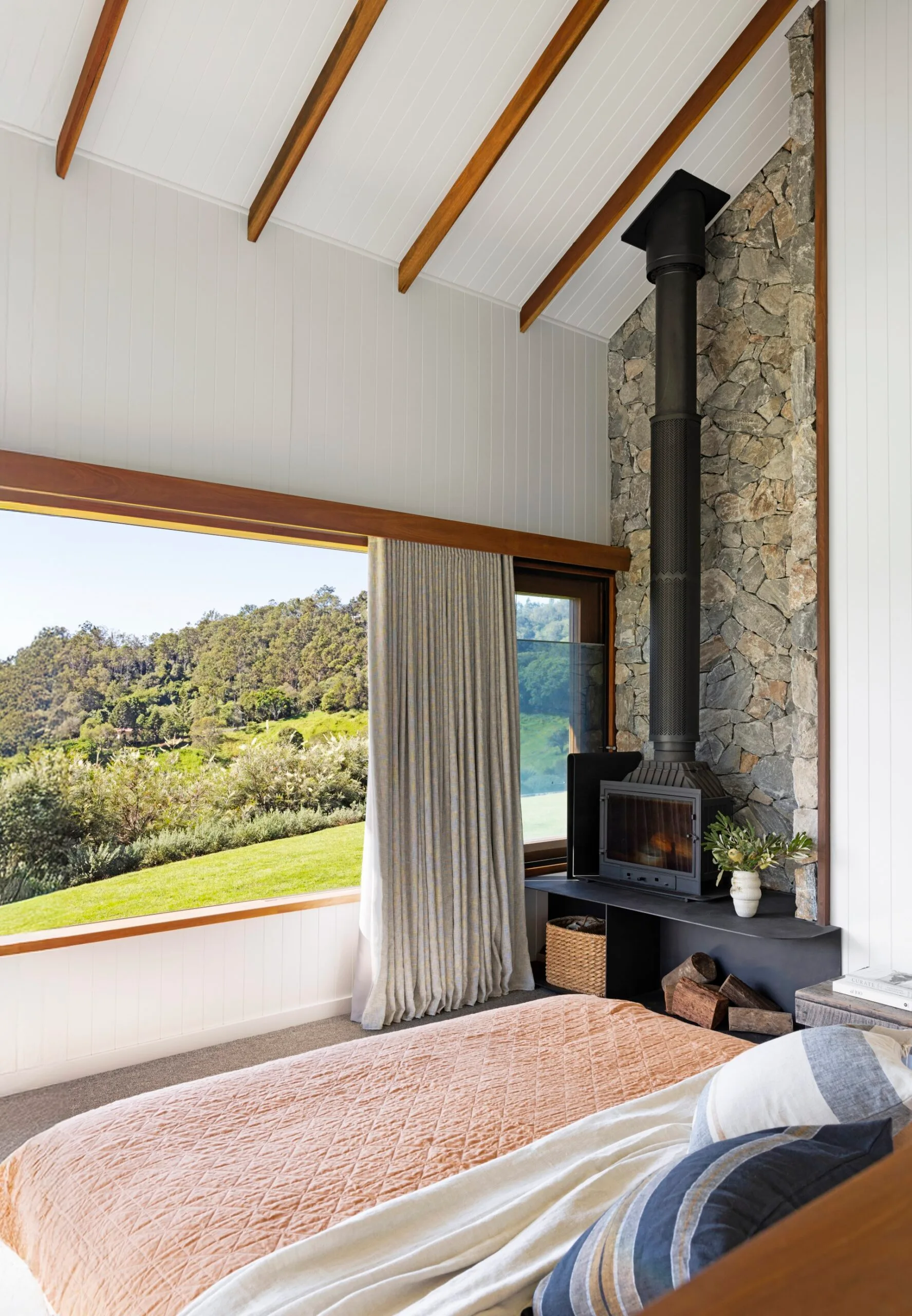 A master bedroom with views out to trees and hills