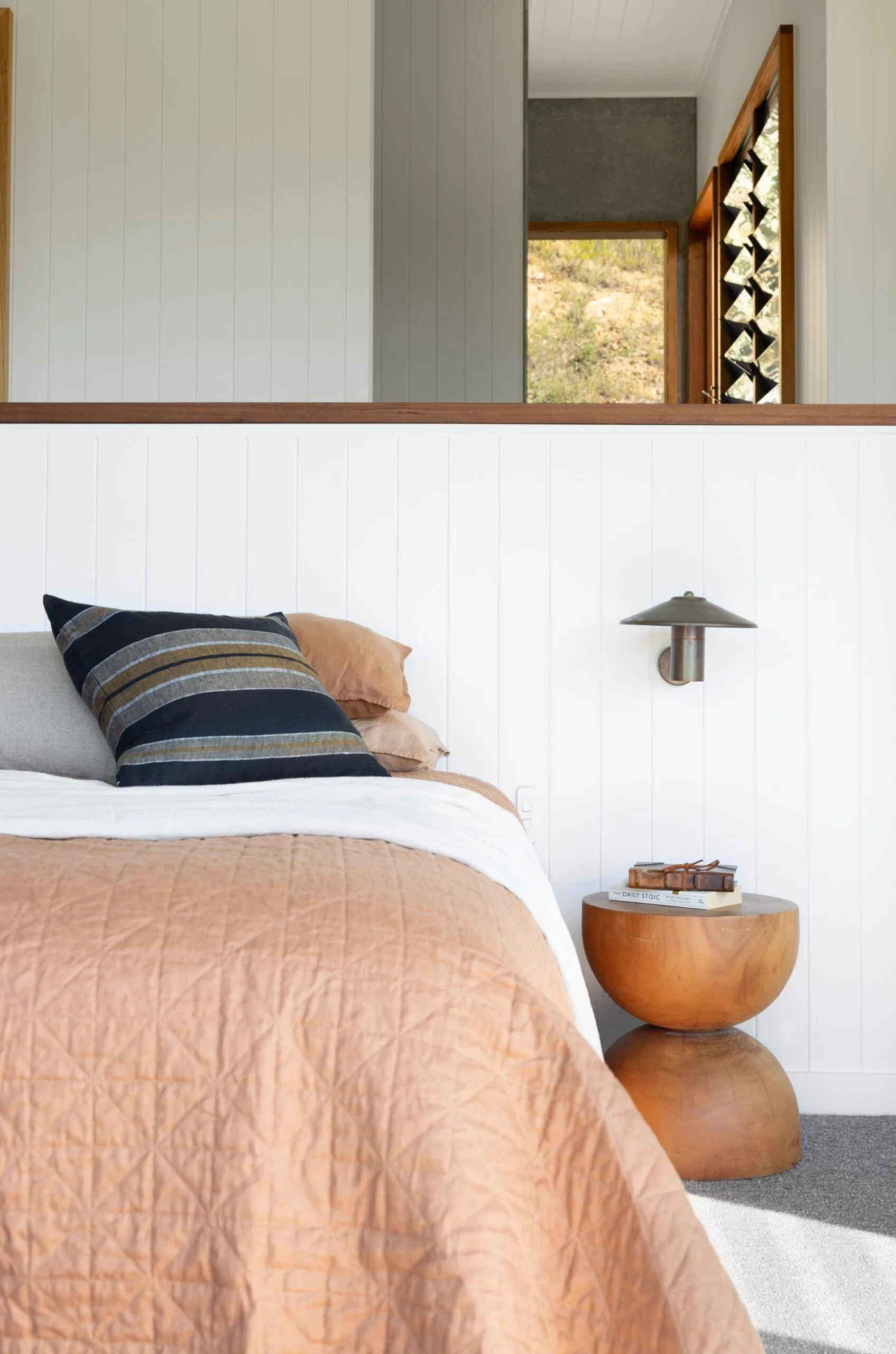 Master bedroom with peachy pink linen and white panelled walls