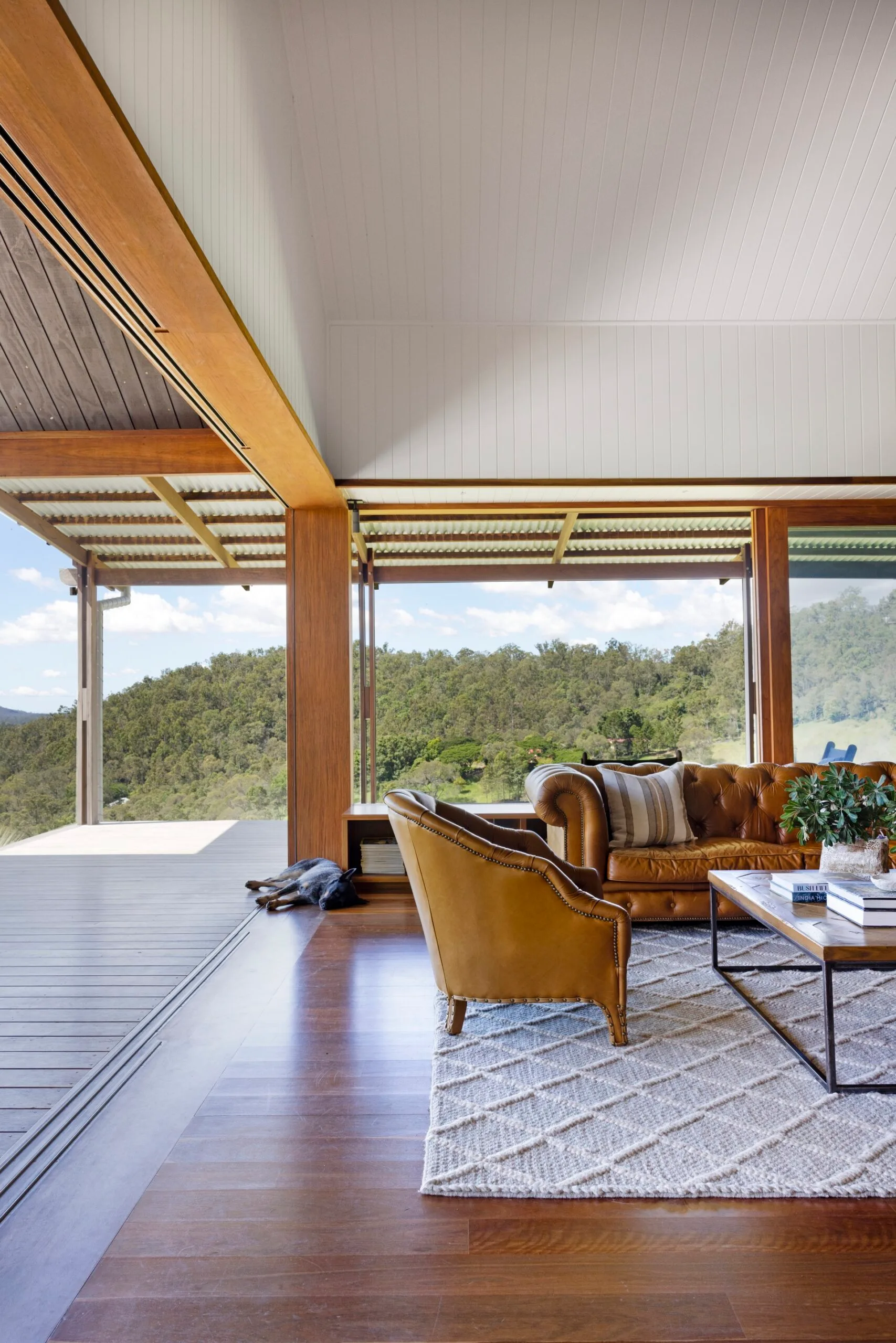 A living room flows onto an outdoor deck with views of trees