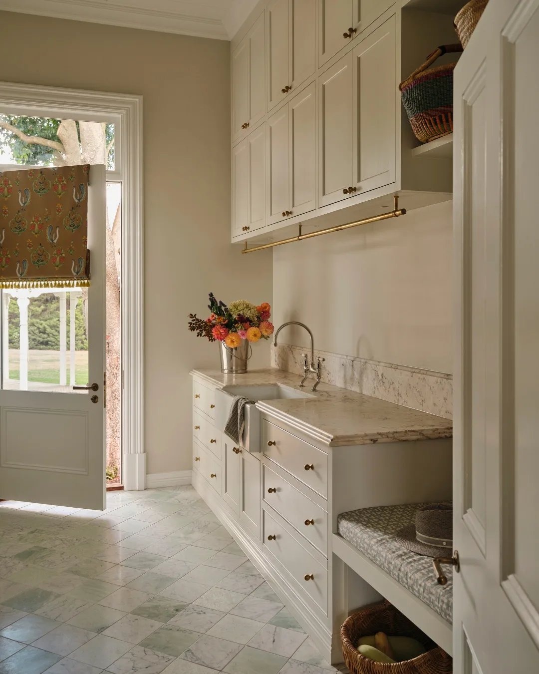 Cream laundry room with light green marble checkerboard floor tiles. The laundry room leads outside with a door slightly ajar. 