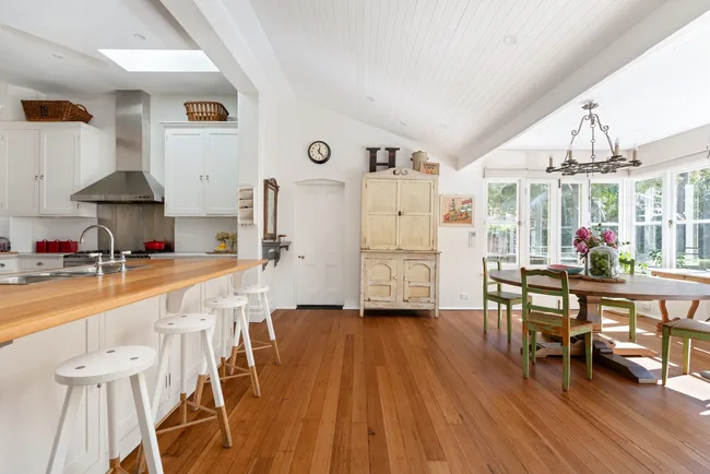 A white open-plan kitchen and dining area with timber floors