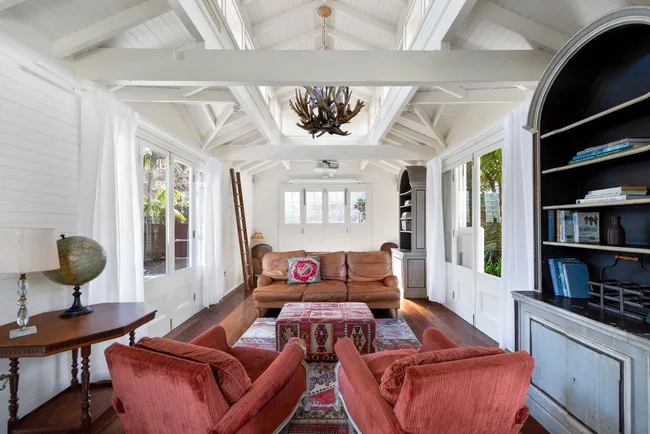 A lounge room with white ceiling beams and bookshelves