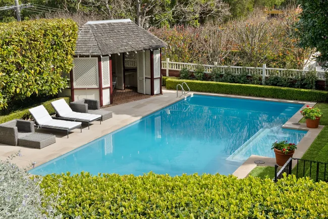 A swimming pool surrounded by hedges