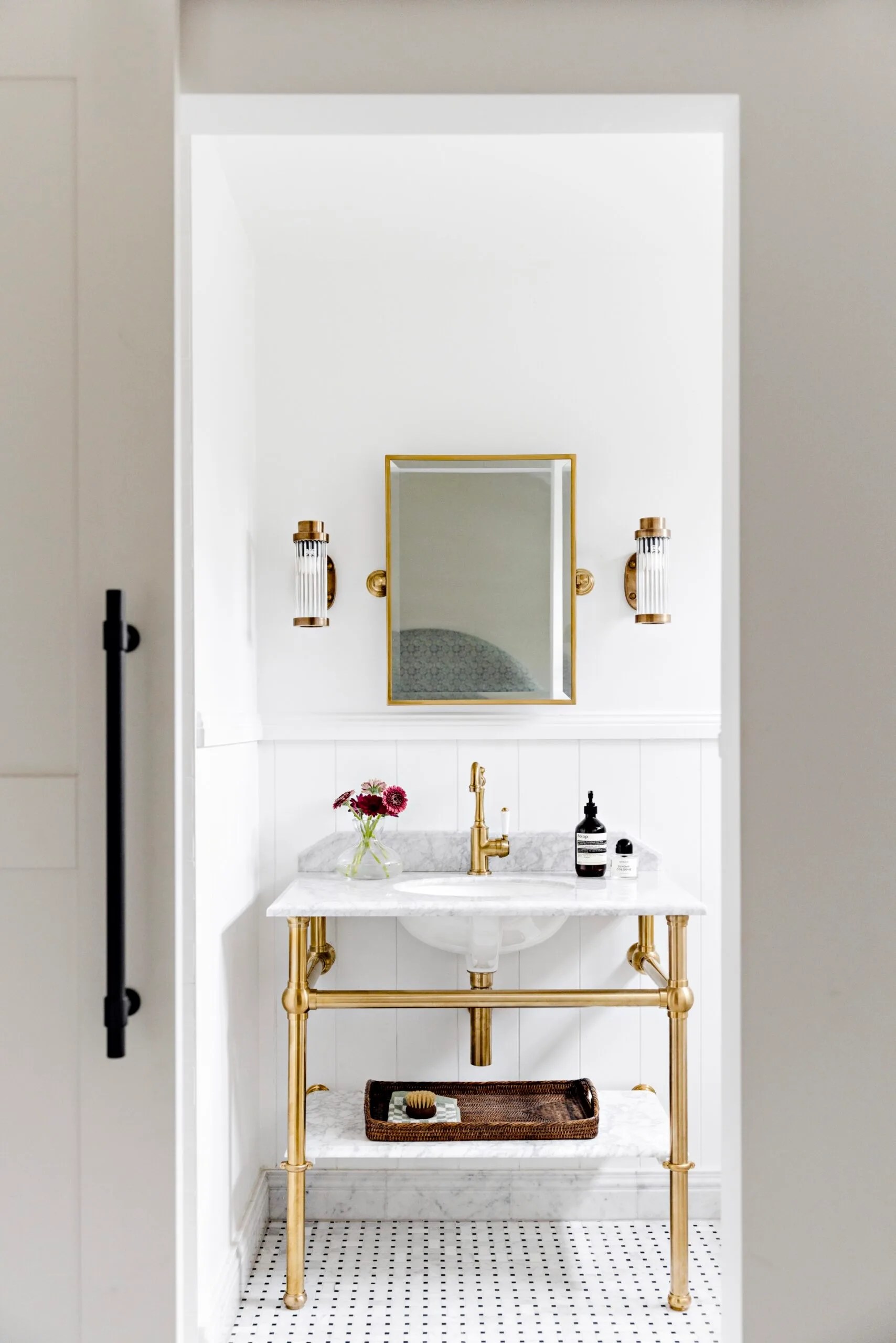 A white bathroom with gold fixures and carrara marble accents.