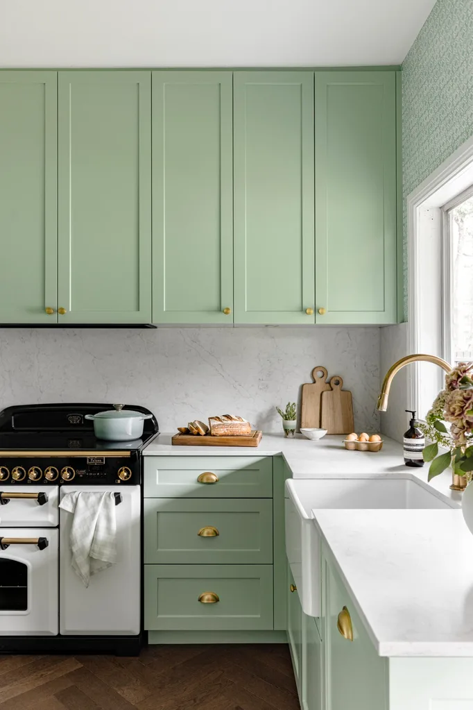 A pale green country kitchen with gold tapware