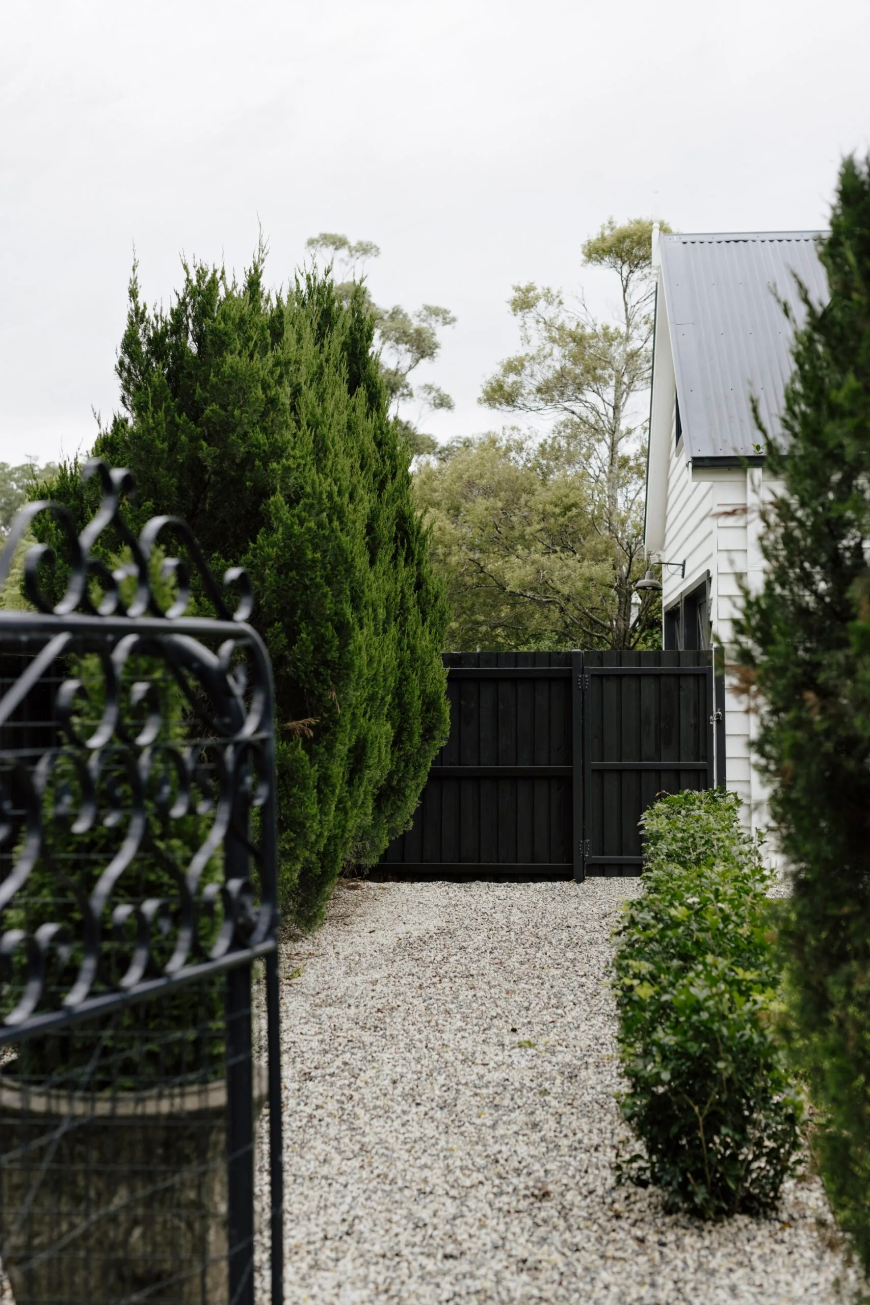 A pebbled laneway in the country lined with plenty of trees and shrubs