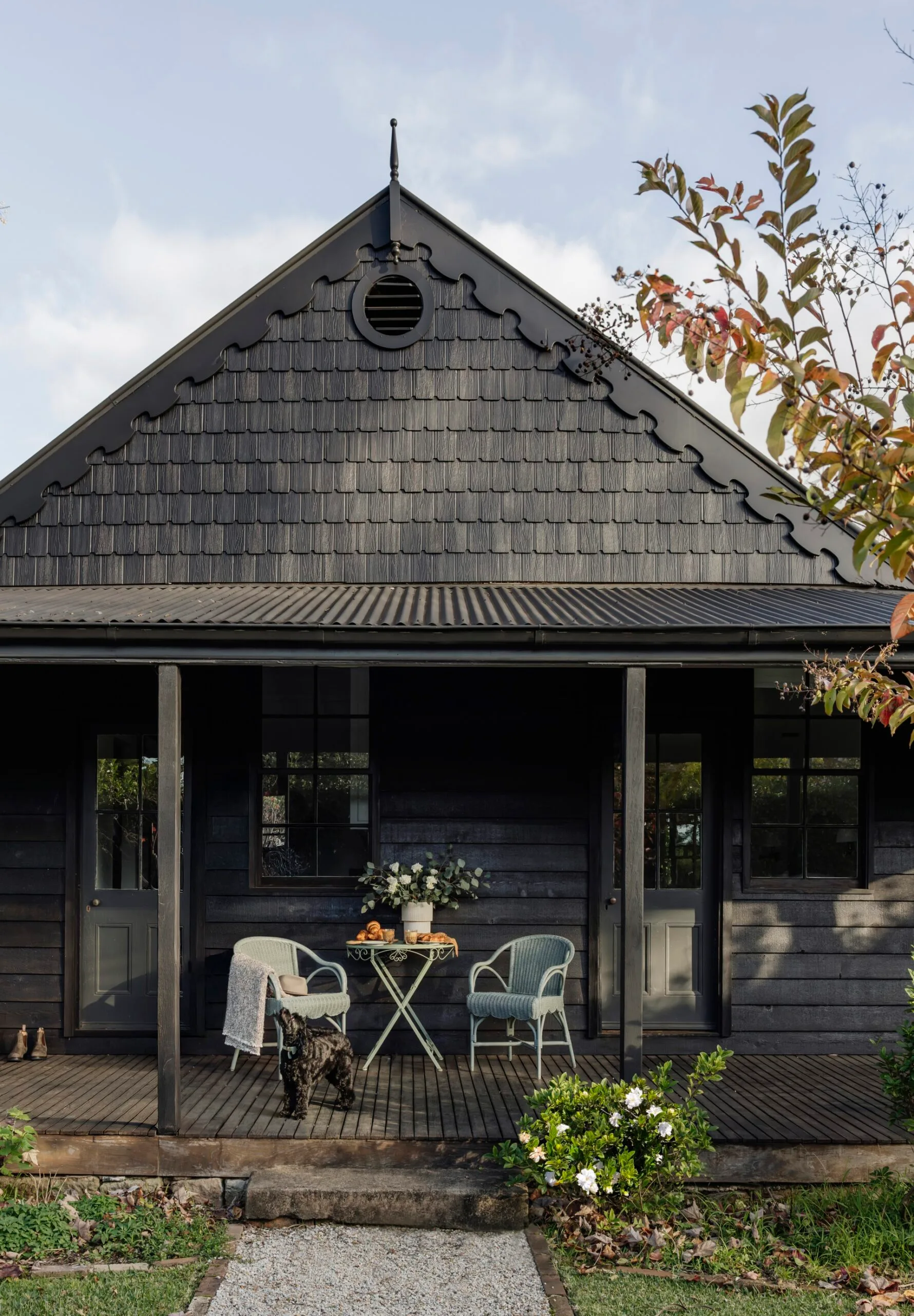 A dark brown cottage with a shingled roof in the country