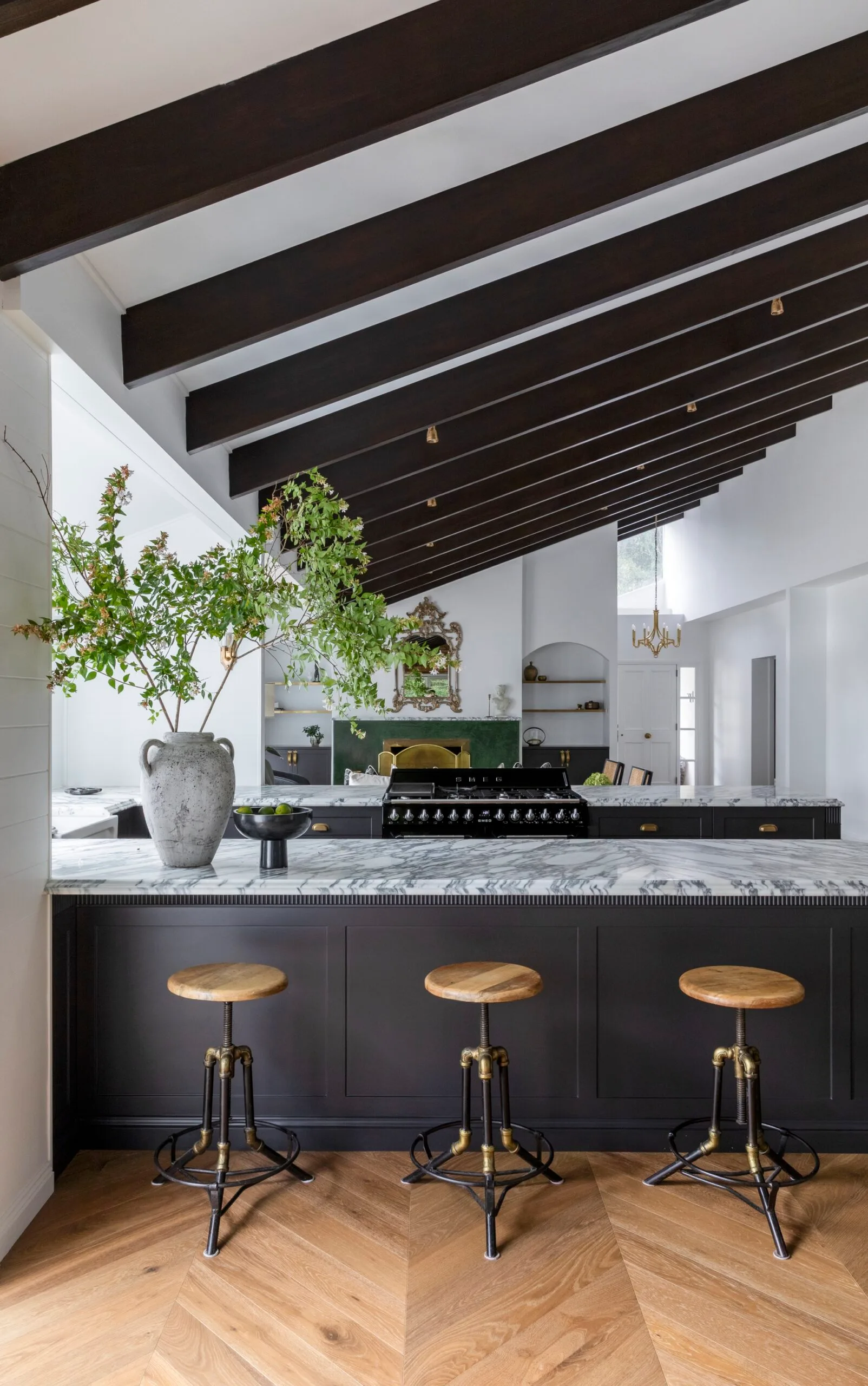 A modern kitchen with marble countertops, parquetry flooring and exposed timber beams
