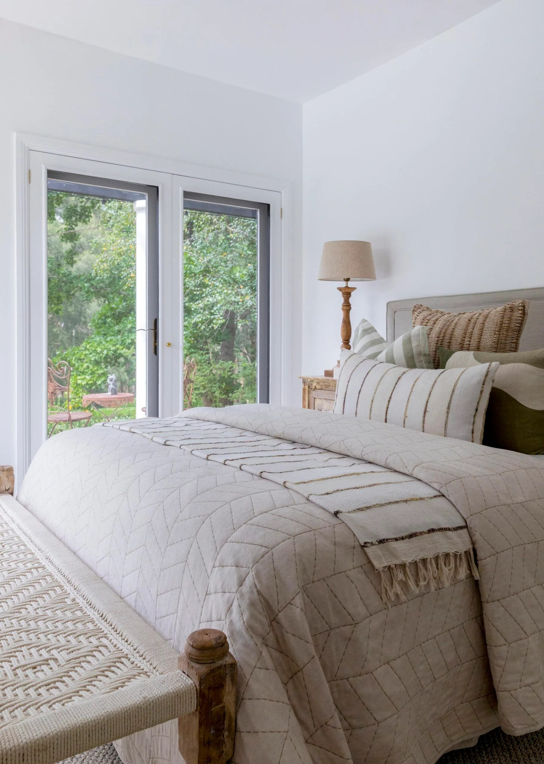 A large bed with beige bedding with garden views
