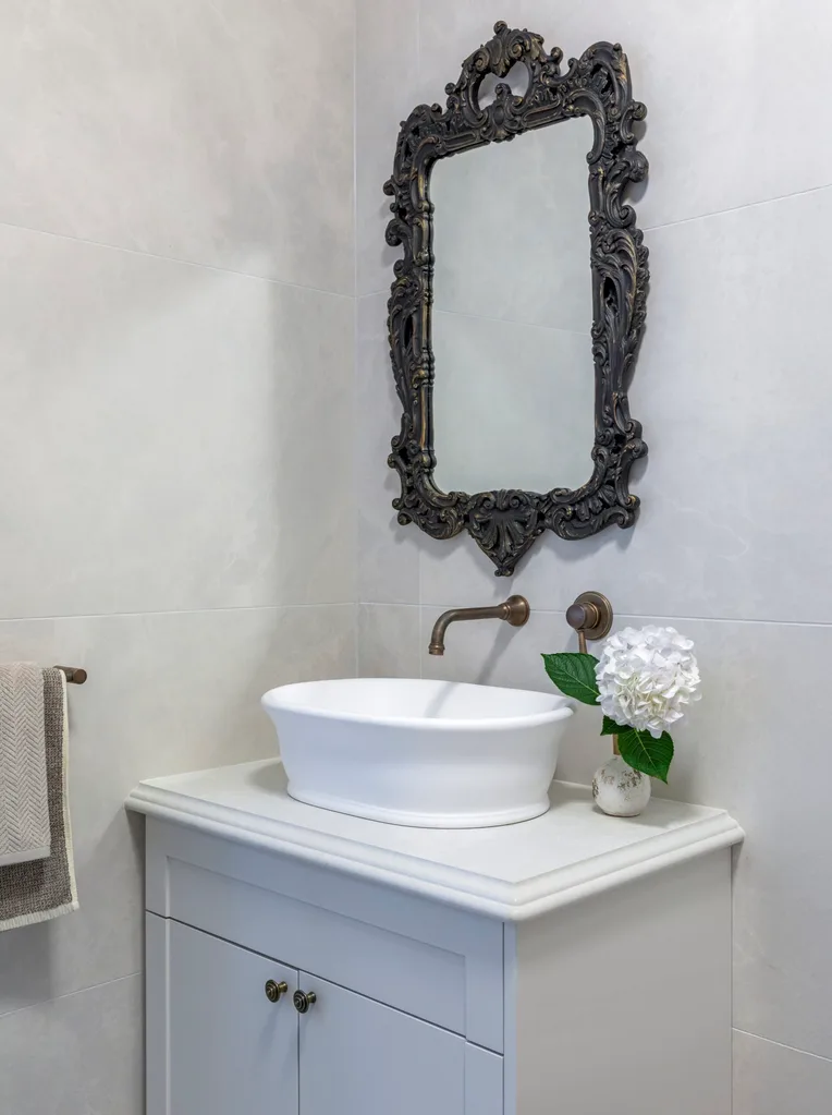 A white vanity with an antique mirror