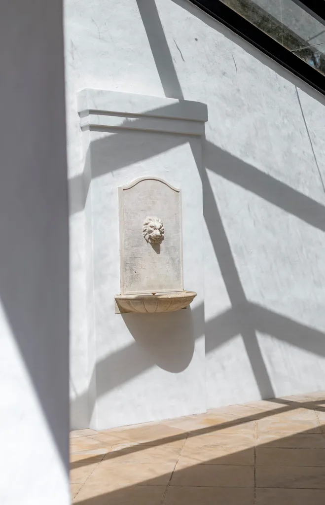 A white wall with a mounted fountain