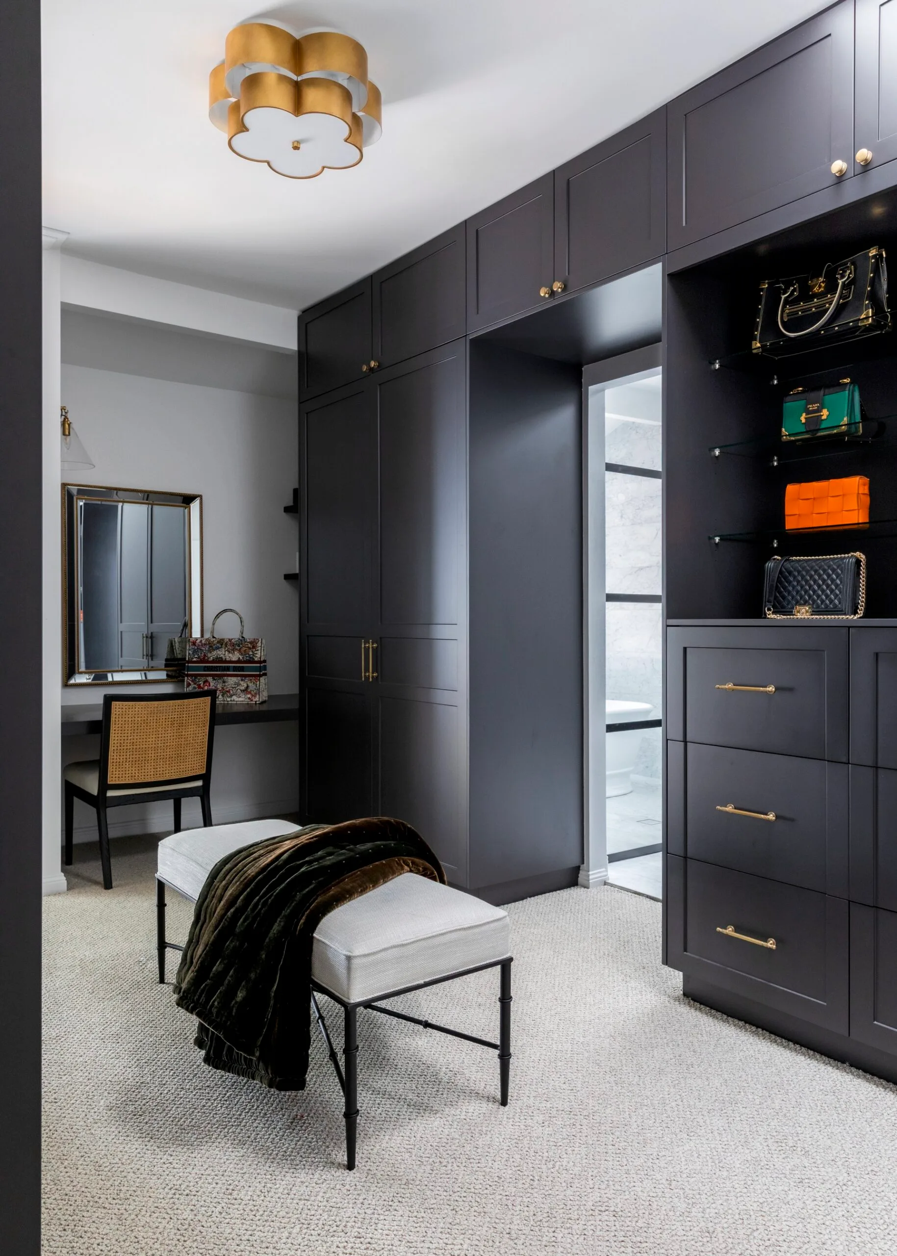 A walk-in wardrobe with dark cabinetry