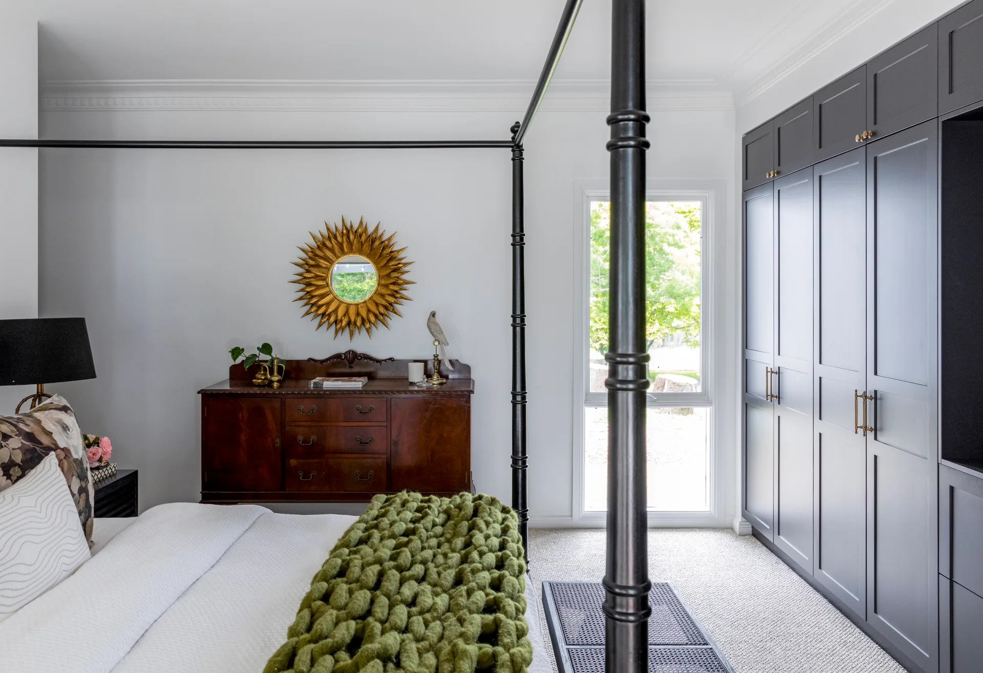 A bedroom with a four-poster bed and dark cabinetry