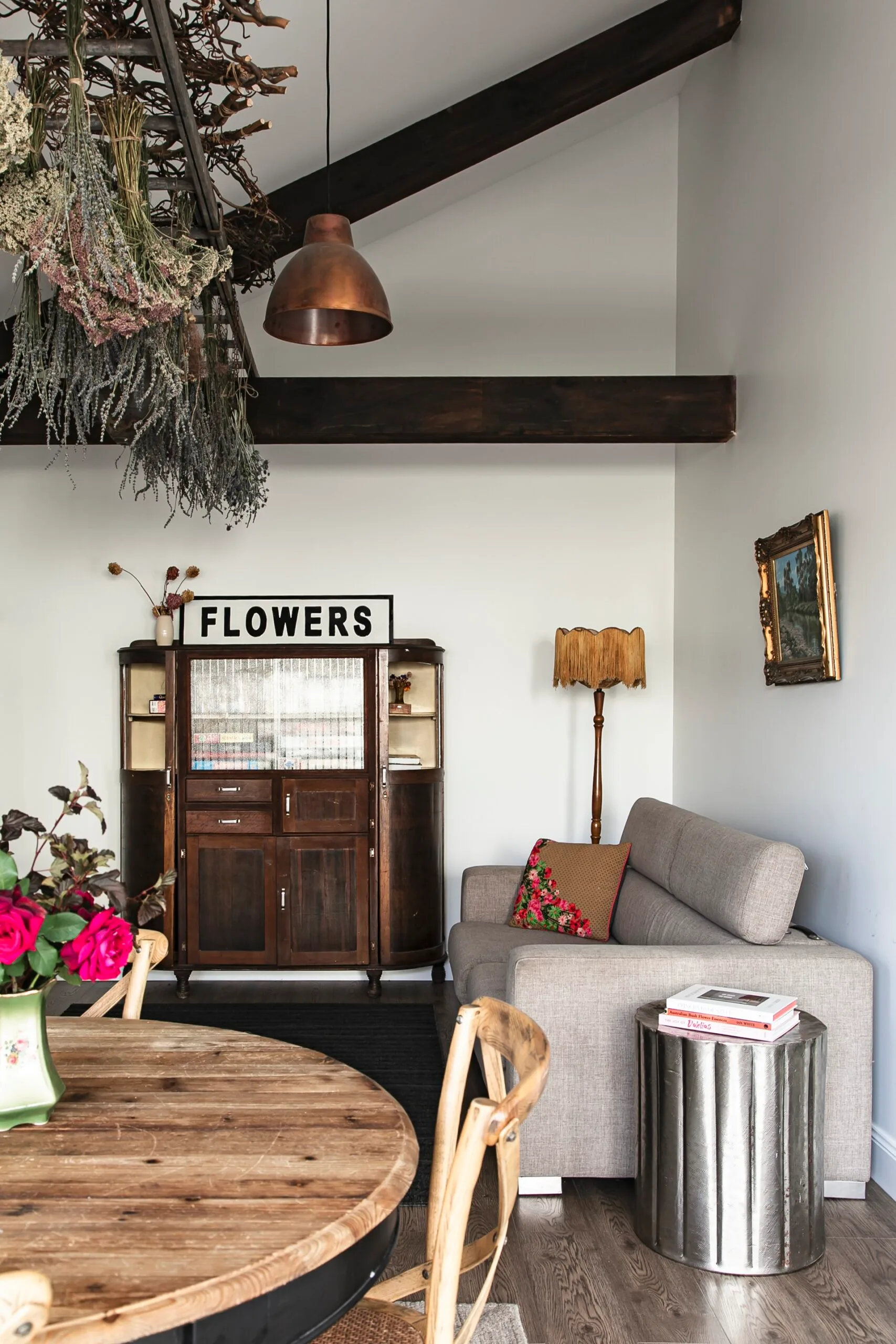 A vintage cabinet with dried flowers in a modern living room.
