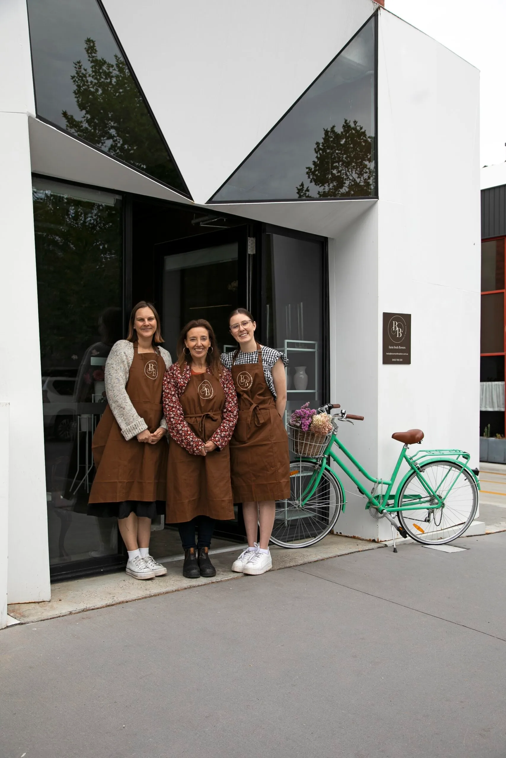 Three ladies outside a flower shop called Blooms of Braddon.