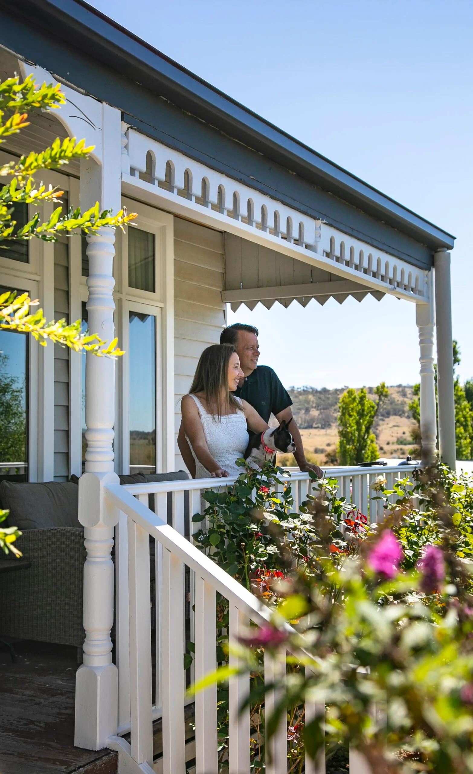 A couple with their dog on the verandah.