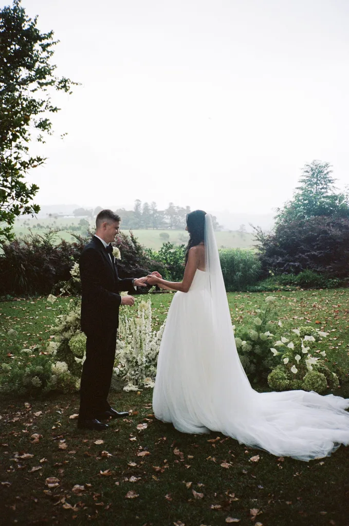 A couple exchange wedding rings in a field