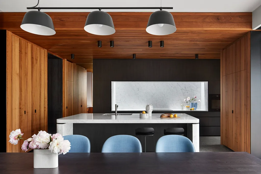 Modern kitchen with warm wood ceiling and blue dining chairs. Belle